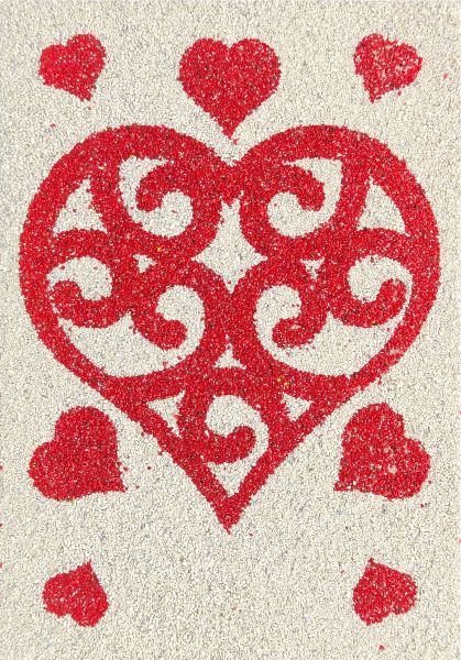 Heart sand painting with red decorative patterns on a textured background.