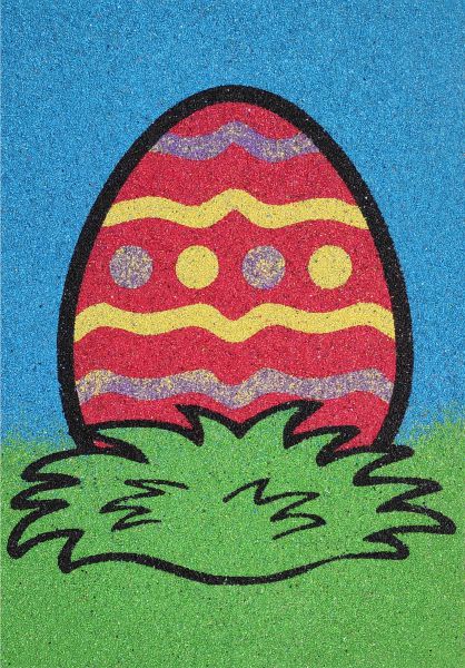 Colorful egg sand art in grass with vibrant patterns.