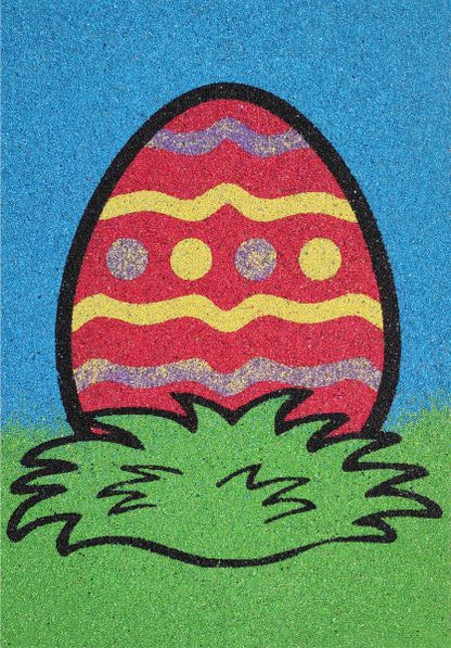 Colorful egg sand art in grass with vibrant patterns.
